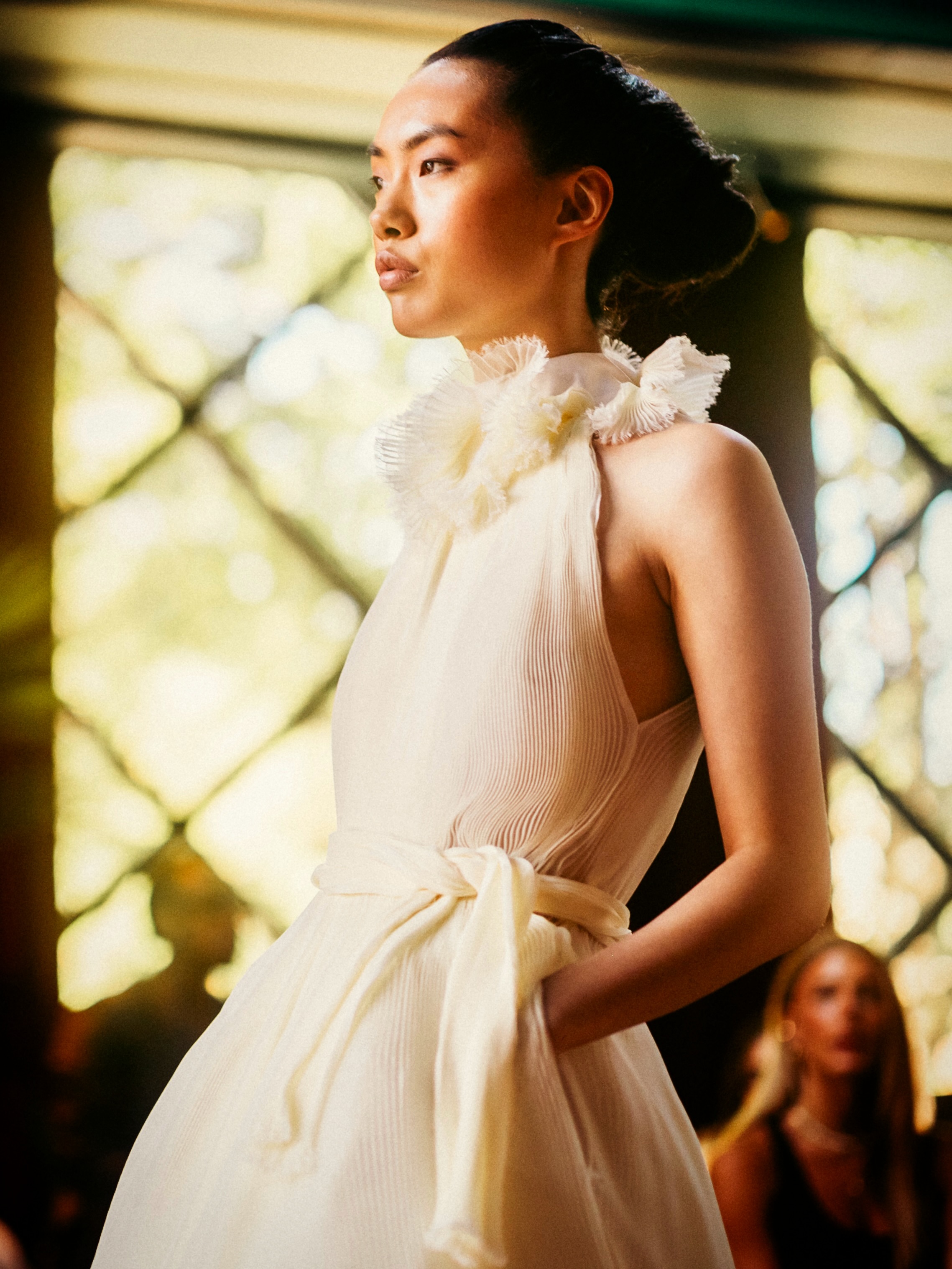 A model presents a white look on the runway.