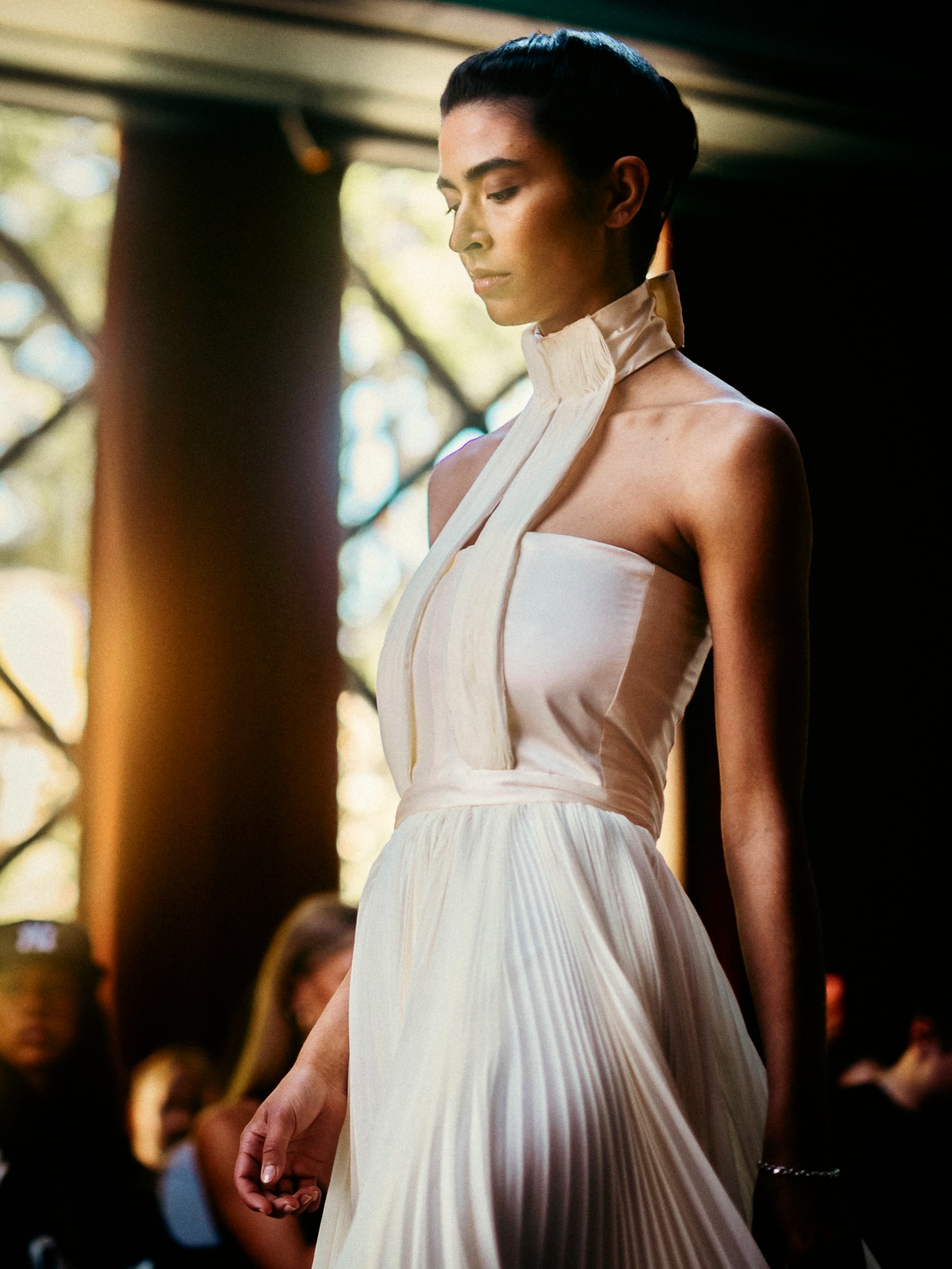 A model presents a white look on the runway.