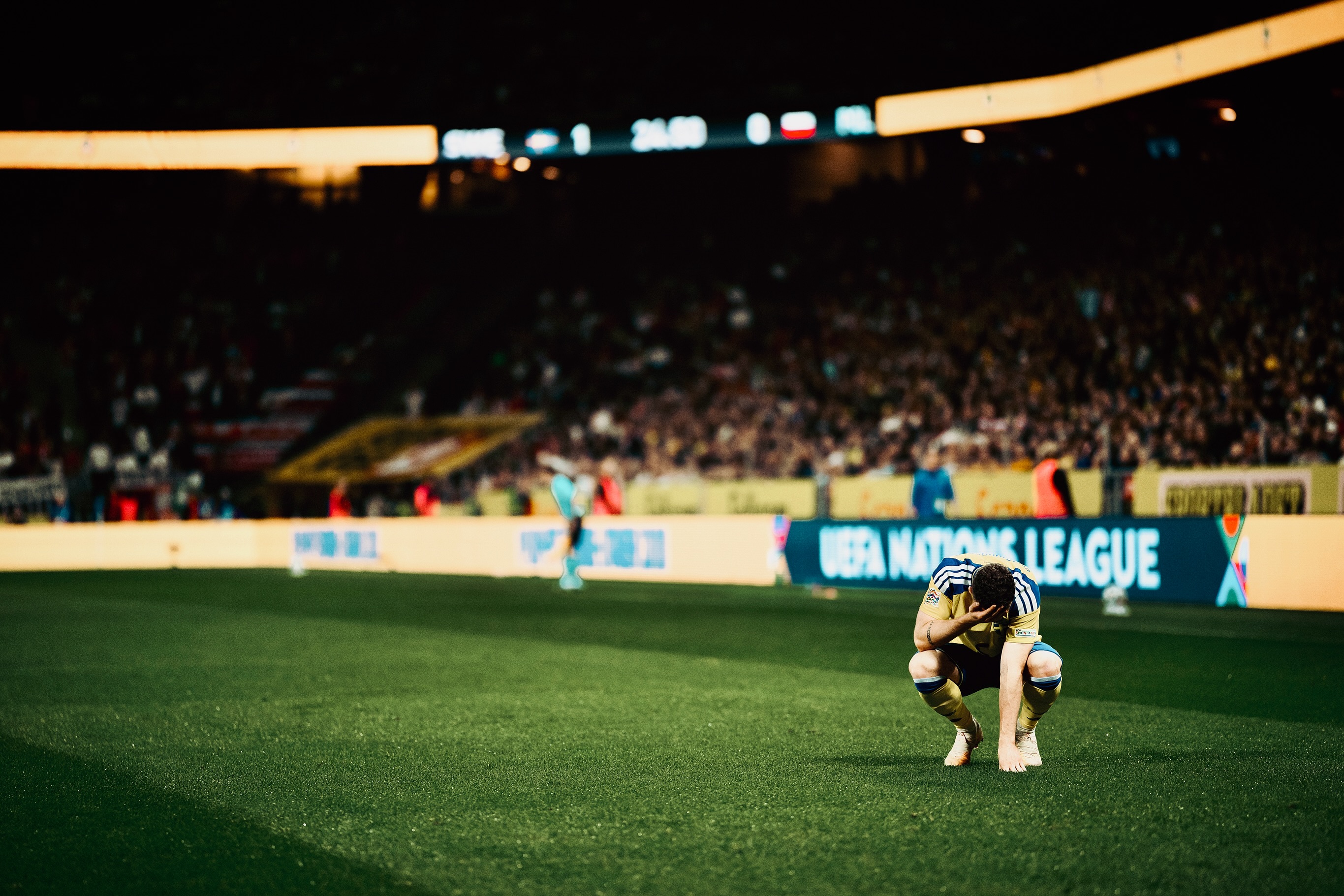 A Swedish player stands near the touchline.