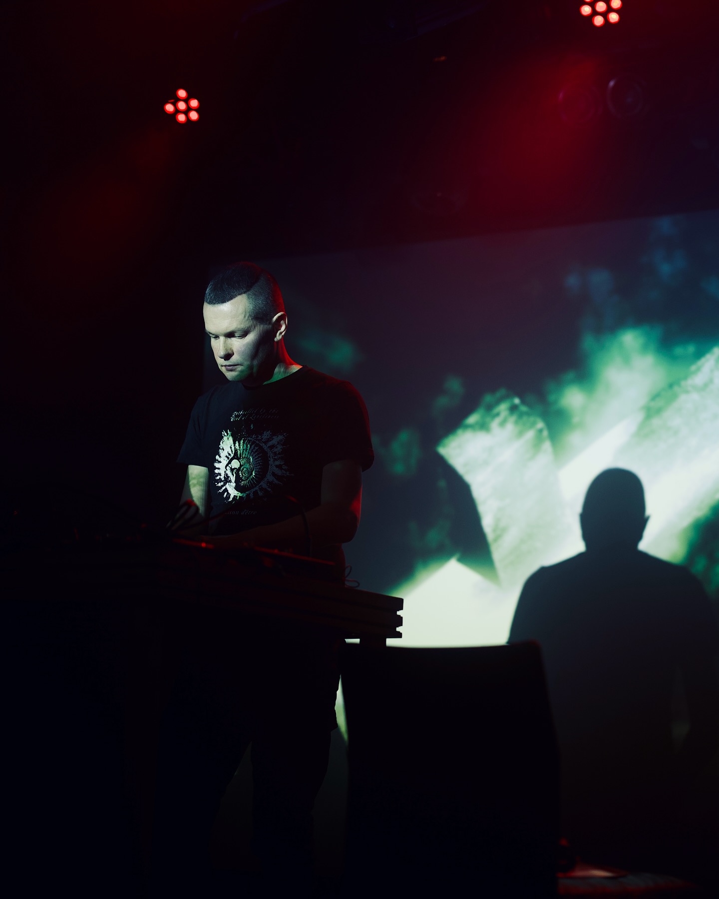 Raison d’être performs at a keyboard beneath stage projections.