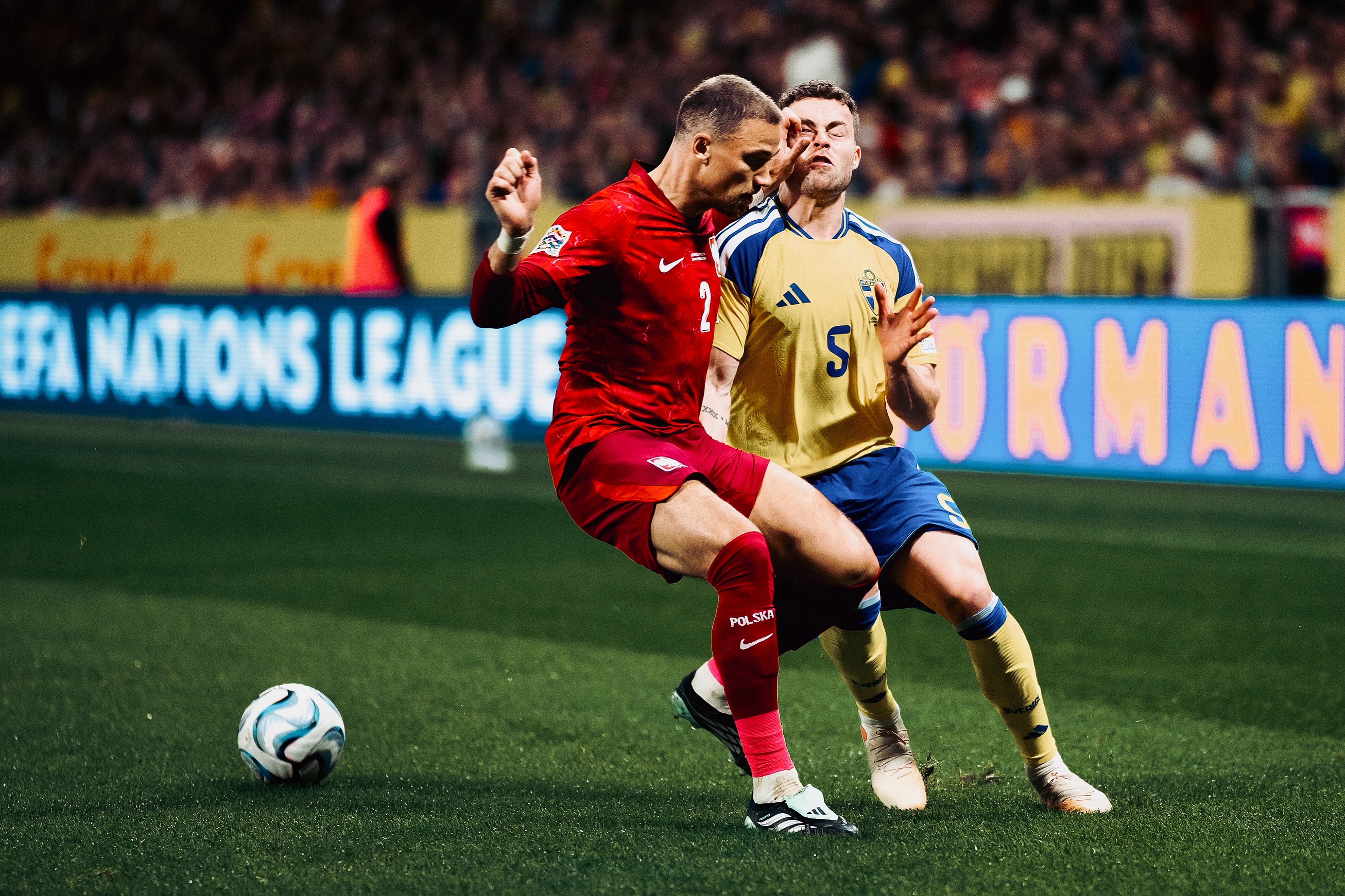 A Swedish and a Polish player challenge for the ball.