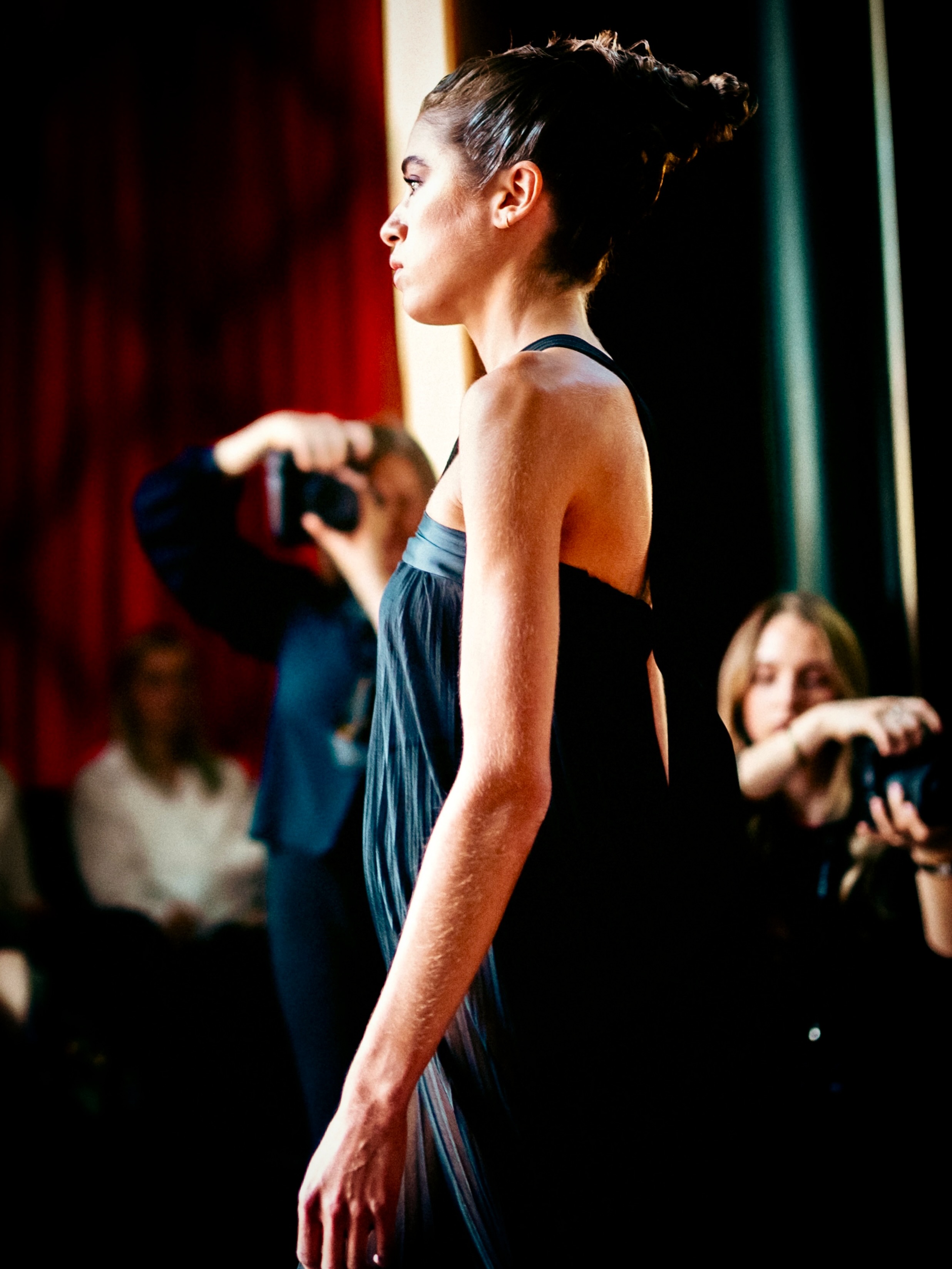 A model presents a dark blue look on the runway.